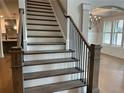 Elegant staircase featuring wood steps, iron spindles, and a decorative chandelier, adds architectural interest at 4050 Sierra Vista Cirs, Cumming, GA 30040