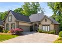 A beige stucco house with a large driveway and a two-car garage door and landscaping on a sunny day at 4569 Fountain Ne Dr, Marietta, GA 30067