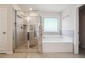 Bathroom with a glass-enclosed shower and separate tub with light-colored neutral tile surround at 3373 Shoals Ridge Dr, Dacula, GA 30019
