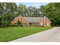 Charming brick home features a lush green lawn, manicured landscaping, and a lengthy driveway at 2297 Ironwood Hill Ct, Dacula, GA 30019