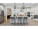 Open kitchen with island seating, stainless appliances, hardwood floors and stylish pendant lighting at 572 Cresentry Brk, Smyrna, GA 30082