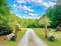 Long gravel driveway, surrounded by lush greenery and rustic decorations, leads to the property at 8032 Banks Mill Rd, Douglasville, GA 30135