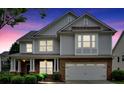 Charming two-story home with a covered front porch illuminated at dusk showcasing its architectural features at 221 Hampton Station Blvd, Canton, GA 30115
