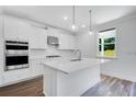 Modern, all-white kitchen features stainless steel appliances, a central island, and stylish pendant lighting at 3311 Burkston Pl, Buford, GA 30519