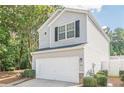 Side view of the home with a 2 car garage, lovely landscaping, and neutral vinyl siding at 606 Windcroft Nw Cir, Acworth, GA 30101