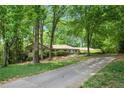 Charming single-story home with lush landscaping and a long driveway, nestled among mature trees at 12080 Mountain Laurel Dr, Roswell, GA 30075