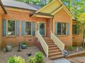 Charming brick home featuring a welcoming entrance with decorative door, shutters, and landscaped front yard at 318 Dogwood Trce, Mcdonough, GA 30252