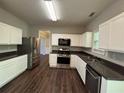 Well-lit kitchen with stainless steel appliances, white cabinets, and dark countertops at 3063 Grace Ct, Lawrenceville, GA 30043