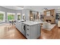 Open-concept kitchen with island, hardwood floors, and stone fireplace at 1440 Water View Ln, Suwanee, GA 30024