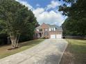 Two-story brick home with a long driveway, attached two-car garage, and mature trees in the front yard at 300 Bermuda Ct, Dallas, GA 30157
