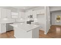 Bright kitchen boasts white cabinets, stainless steel appliances, island, and wood flooring at 488 Village Ln, Fairburn, GA 30213