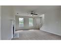 Bright living room features a ceiling fan, plush carpet, and staircase access at 64 Dogwood Rdg, Hampton, GA 30228