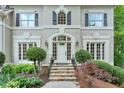 Inviting front entrance with stone steps, lush landscaping, and an elegant arched doorway and manicured shrubbery at 9900 Hunt Club Way, Johns Creek, GA 30022