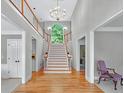 Elegant foyer with hardwood floors, staircase, chandelier, and a view to the upper level landing at 9900 Hunt Club Way, Johns Creek, GA 30022