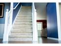 Carpeted staircase with white railing, leading to a home's upper level, with hardwood floors in the foyer at 4041 Smithfield Trl, Ellenwood, GA 30294