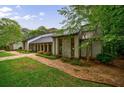 Beautiful one-story home with stone details, dark metal roof, surrounded by mature trees at 5120 Jett Forest Trl, Atlanta, GA 30327