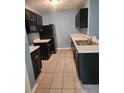 Kitchen with black cabinetry, stainless steel sink, white countertops, and tiled floors at 5574 Fair Creek Way, Lithonia, GA 30038