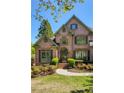 Charming brick facade of the home complemented by lush landscaping at 6185 Deerwoods Trl, Alpharetta, GA 30005