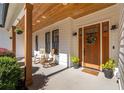 Inviting front porch with wood columns, rocking chairs, hanging plants, and a stylish wood front door at 9770 Coleman Rd, Roswell, GA 30075