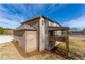 A rear view of a brick house featuring a covered patio and a view of the lake beyond the lawn at 4040 Sierra Vista Cir, Cumming, GA 30040