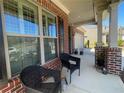 Inviting front porch with brick columns, dark wicker seating, and well-maintained landscaping at 448 Marston Pass, Acworth, GA 30102