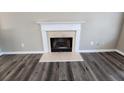 Close-up of fireplace with white mantel and light-colored stone hearth and surround on dark floors at 4510 Swan Trce, Atlanta, GA 30349