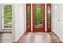 A foyer with a beautiful glass paneled front door and wood floors, next to a bright window at 475 Nottingham Dr, Marietta, GA 30066