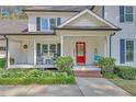 Inviting front porch with rocking chairs and a vibrant red door surrounded by lush greenery at 4985 Miller Sw Rd, Lilburn, GA 30047