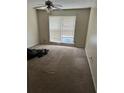 A large bedroom with neutral carpeting, a ceiling fan, and a window for natural light at 102 Governors Dr, Forest Park, GA 30297