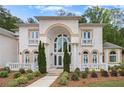 Stately home featuring a grand arched entryway, white brick, and well-maintained landscaping at 2425 Wild Oak Ct, Stockbridge, GA 30281
