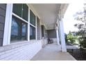 Covered front porch with white brick base, large windows, and an inviting seating area at 125 Leveret Rd, Locust Grove, GA 30248
