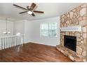 Inviting living room featuring a stone fireplace, a ceiling fan, and hardwood flooring at 2636 Suzanne Ln, Acworth, GA 30102