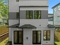 Rear exterior elevation of a modern home, highlighting the light-colored siding, dark window frames, and manicured backyard at 90 Cleveland Unit B Se St, Atlanta, GA 30316