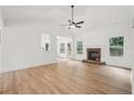 Bright living room with a fireplace, wood flooring, large windows, and a ceiling fan at 2279 Lakeview Pkwy, Villa Rica, GA 30180