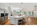 Bright kitchen featuring stainless steel appliances, white cabinetry, an island and hardwood floors at 4585 Lakefield Bnd, Berkeley Lake, GA 30096