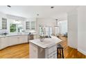 Open kitchen featuring white cabinets, an island with seating, and stainless steel appliances and hardwood floors at 4585 Lakefield Bnd, Berkeley Lake, GA 30096