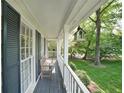 Cozy covered porch with a wooden bench, offering a relaxing outdoor space with a view of the landscaped yard at 4739 Bradford Ln, Powder Springs, GA 30127