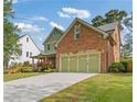 Side view of a brick home showcasing the three-car garage and green lawn at 2853 N Thompson Ne Rd, Brookhaven, GA 30319