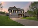 Charming two-story home featuring gray siding, black shutters, and a well-maintained front yard at dusk at 577 Joneus Dr, Mcdonough, GA 30252