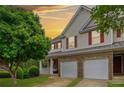 Exterior showcasing sunset views, a covered porch, a two-car garage, and a well-manicured front yard at 138 Fox Creek Dr, Woodstock, GA 30188