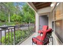 Relaxing outdoor balcony space featuring two red cushioned chairs with a view of greenery and the neighborhood street at 5559 Glenridge Dr # 1103, Sandy Springs, GA 30342