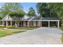 Charming single story brick home with manicured lawn, mature trees, and covered carport at 825 Loridans Ne Cir, Atlanta, GA 30342