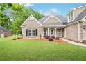 Beautiful exterior of a brick home with a well-maintained lawn and charming front porch with decorative chairs at 1593 Fredricksberg Dr, Loganville, GA 30052
