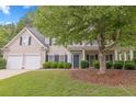 Charming two-story home with a well-manicured lawn, mature trees, and a two-car garage at 6131 Windflower Dr, Powder Springs, GA 30127