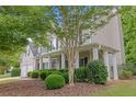 Low angle view of the home featuring the front yard, landscaping, and front porch with columns at 6131 Windflower Dr, Powder Springs, GA 30127