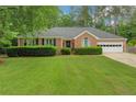 Beautiful brick home with lush green lawn, trimmed bushes, and a two-car garage at 1050 Chestnut Hill Sw Cir, Marietta, GA 30064