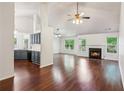 Open-concept living area featuring a fireplace, hardwood floors, vaulted ceiling, and neutral paint at 672 Bostonian Way, Lawrenceville, GA 30046