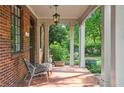 Relaxing front porch featuring red brick, stately columns, and views of the garden at 26 Clarendon Ave, Avondale Estates, GA 30002