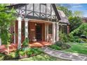 Close up of inviting front porch, featuring red brick, white columns, and lush landscaping at 26 Clarendon Ave, Avondale Estates, GA 30002