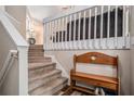 Warm entryway with carpeted stairs, wooden bench, and white railings, offering a cozy and inviting welcome at 300 Alcovy Way, Covington, GA 30014